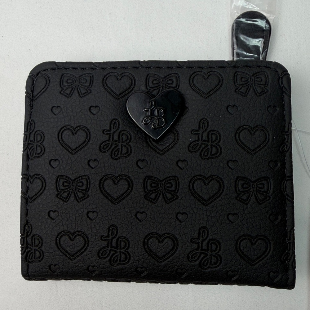 Betsey Johnson Snap Flap French Wallet in black with a heart and bow pattern.